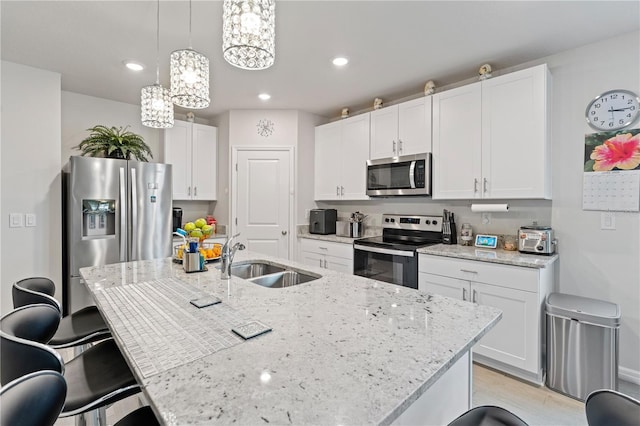 39024 Harlow Rose Dr, Zephyrhills, FL 33540 - kitchen with stainless steel appliances, a chandelier, a breakfast bar, white cabinetry, and light stone countertops