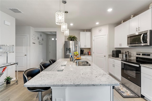 39024 Harlow Rose Dr, Zephyrhills, FL 33540 - kitchen featuring appliances with stainless steel finishes, a kitchen breakfast bar, light wood finished floors, white cabinetry, and recessed lighting
