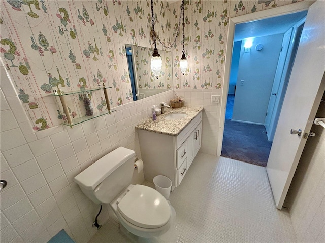 2070 World Parkway Blvd Unit 36, Clearwater, FL 33763 - bathroom with wallpapered walls, tile patterned flooring, tile walls, vanity, and a wainscoted wall