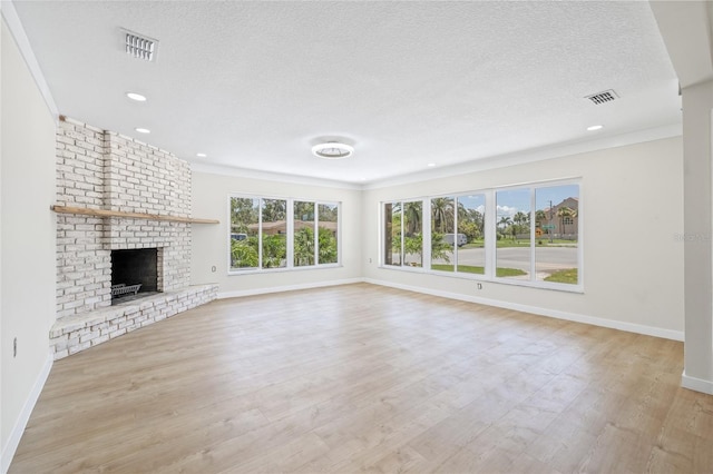 6400 Mockingbird Way S, Saint Petersburg, FL 33707 - unfurnished living room with a textured ceiling, light wood finished floors, a fireplace, recessed lighting, and crown molding