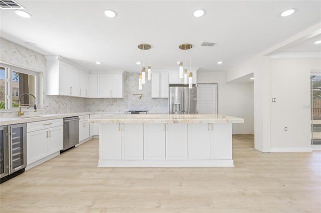 6400 Mockingbird Way S, Saint Petersburg, FL 33707 - kitchen with stainless steel appliances, beverage cooler, a center island, white cabinets, and light wood finished floors
