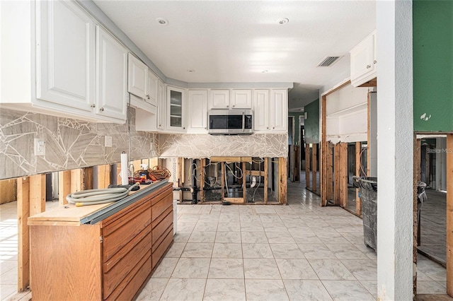 4928 Petunia Ct, New Port Richey, FL 34652 - kitchen featuring stainless steel microwave, white cabinets, and glass insert cabinets
