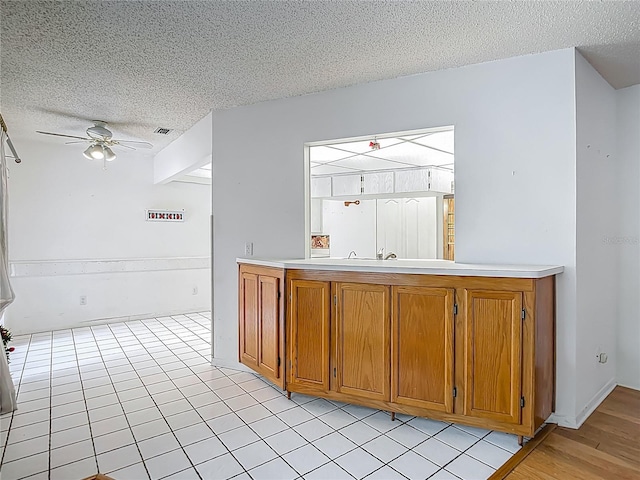 1607 New Bedford Dr, Sun City Center, FL 33573 - kitchen featuring a textured ceiling, brown cabinets, a ceiling fan, and light countertops