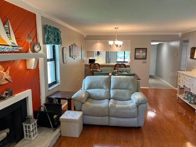 140 Nina Way, Oldsmar, FL 34677 - living room with wood finished floors, a chandelier, a fireplace, and crown molding