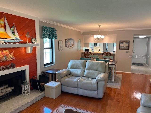 140 Nina Way, Oldsmar, FL 34677 - living area featuring wood finished floors, a chandelier, crown molding, and a fireplace with raised hearth