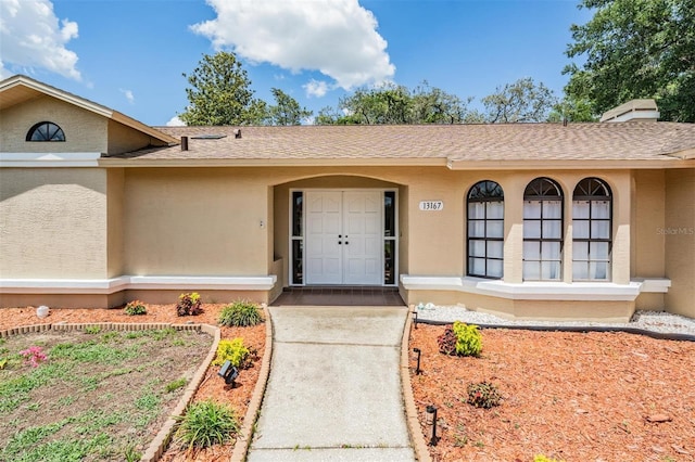 13167 Roseanna Dr, Spring Hill, FL 34609 - view of exterior entry with roof with shingles and stucco siding