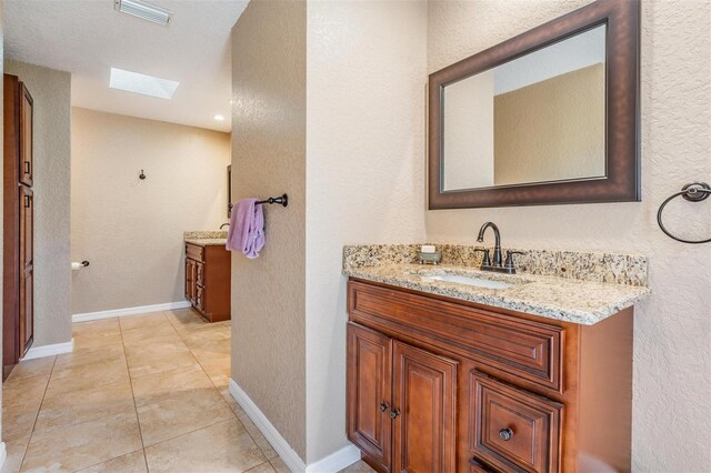 13167 Roseanna Dr, Spring Hill, FL 34609 - bathroom with vanity, a skylight, a textured wall, and tile patterned flooring