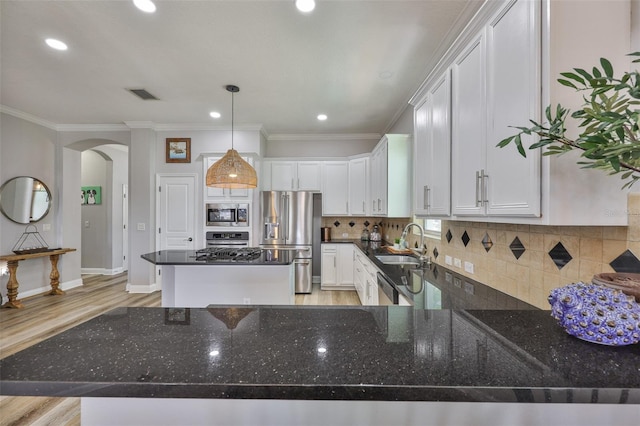 5710 Tortoise Pl, Apollo Beach, FL 33572 - kitchen featuring stainless steel appliances, arched walkways, a center island, light wood finished floors, and white cabinetry