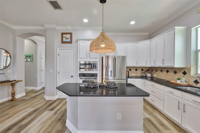 5710 Tortoise Pl, Apollo Beach, FL 33572 - kitchen featuring stainless steel appliances, arched walkways, white cabinetry, dark countertops, and ornamental molding
