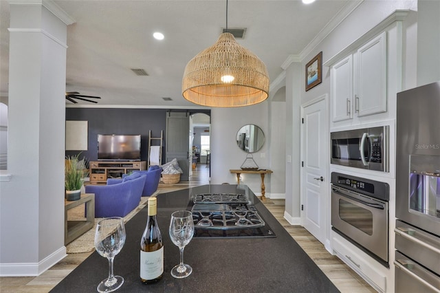 5710 Tortoise Pl, Apollo Beach, FL 33572 - kitchen with stainless steel appliances, light wood-style floors, crown molding, white cabinets, and hanging light fixtures