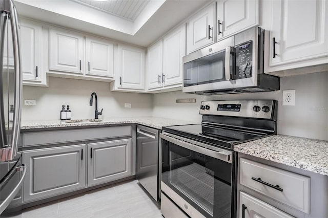 2901 W 26th St Unit 301, Bradenton, FL 34205 - kitchen with appliances with stainless steel finishes, gray cabinets, white cabinets, and light stone counters