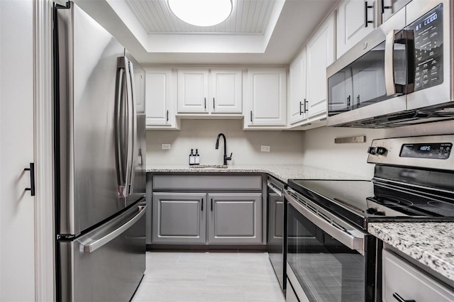 2901 W 26th St Unit 301, Bradenton, FL 34205 - kitchen featuring appliances with stainless steel finishes, gray cabinets, a tray ceiling, and white cabinets