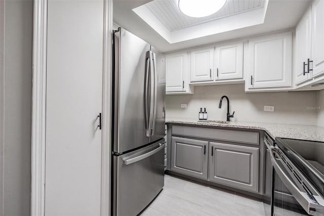 2901 W 26th St Unit 301, Bradenton, FL 34205 - kitchen featuring freestanding refrigerator, gray cabinets, a tray ceiling, electric range oven, and white cabinets