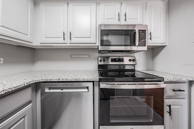 2901 W 26th St Unit 301, Bradenton, FL 34205 - kitchen with appliances with stainless steel finishes, white cabinets, and light stone counters
