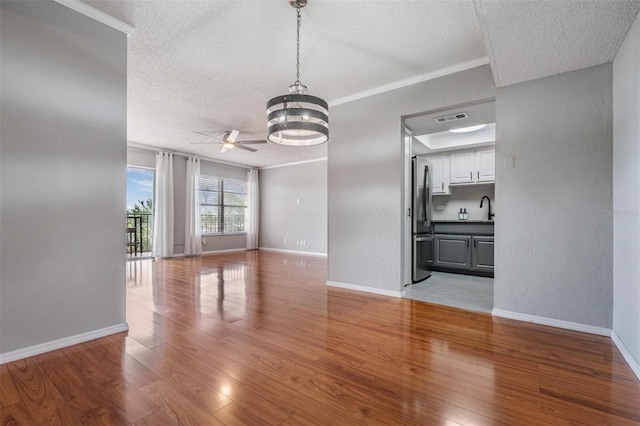 2901 W 26th St Unit 301, Bradenton, FL 34205 - unfurnished living room with a textured ceiling, a ceiling fan, light wood finished floors, a chandelier, and ornamental molding