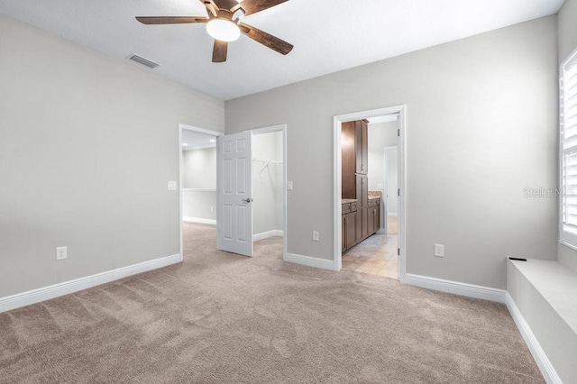 21675 Amelia Rose Way, Land O Lakes, FL 34637 - unfurnished bedroom featuring light carpet, a spacious closet, a closet, ensuite bathroom, and ceiling fan