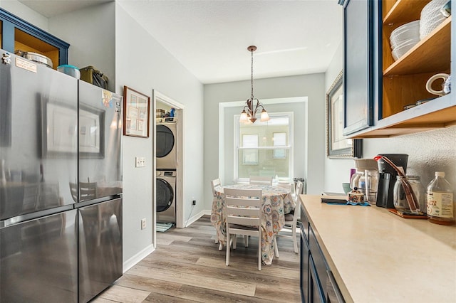 247 Winthrop Dr, Spring Hill, FL 34609 - kitchen featuring freestanding refrigerator, stacked washing machine and dryer, light wood finished floors, light countertops, and pendant lighting