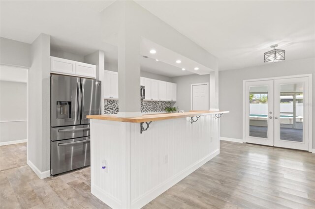 6012 Flora Ter, Apollo Beach, FL 33572 - kitchen with stainless steel appliances, white cabinetry, a kitchen bar, recessed lighting, and backsplash