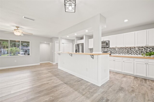 6012 Flora Ter, Apollo Beach, FL 33572 - kitchen with appliances with stainless steel finishes, a kitchen breakfast bar, tasteful backsplash, white cabinetry, and recessed lighting