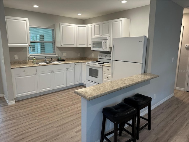 7651 46th Way N, Pinellas Park, FL 33781 - kitchen featuring white appliances, light wood-style flooring, a kitchen breakfast bar, white cabinetry, and recessed lighting