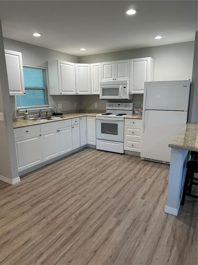 7651 46th Way N, Pinellas Park, FL 33781 - kitchen featuring white appliances, light wood-style flooring, white cabinets, and recessed lighting