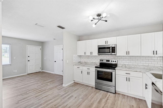 7891 67th St N, Pinellas Park, FL 33781 - kitchen with stainless steel appliances, decorative backsplash, light wood-type flooring, a chandelier, and white cabinets