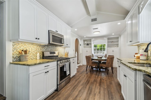 1208 E Crenshaw St, Tampa, FL 33604 - kitchen with appliances with stainless steel finishes, arched walkways, white cabinetry, dark wood-style floors, and backsplash