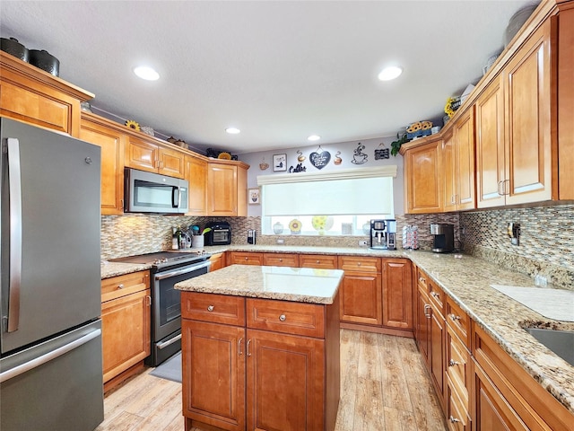 8110 Damara Dr, New Port Richey, FL 34653 - kitchen featuring stainless steel appliances, light wood-type flooring, backsplash, light stone counters, and a center island