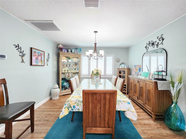 8110 Damara Dr, New Port Richey, FL 34653 - dining room with a chandelier, a textured ceiling, and light wood-style floors