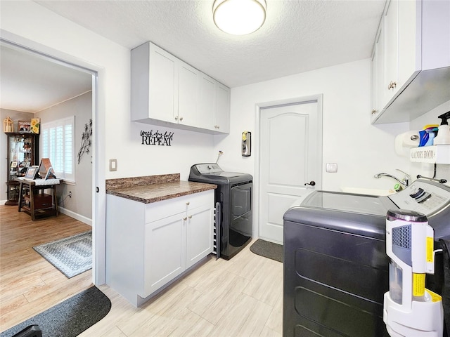 8110 Damara Dr, New Port Richey, FL 34653 - laundry area featuring cabinet space, washer and clothes dryer, a textured ceiling, and light wood-style floors
