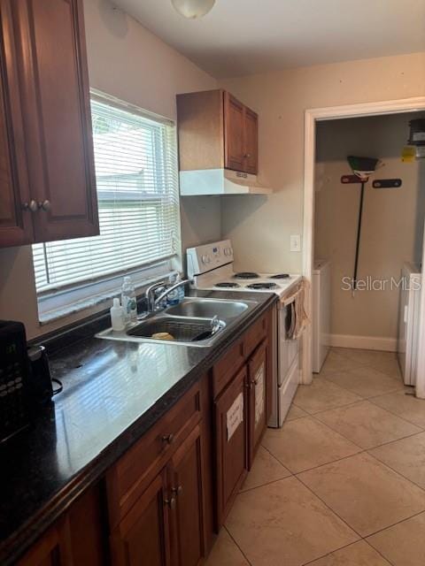 1021 16th Ave SW, Largo, FL 33770 - kitchen with electric range, under cabinet range hood, dark countertops, washer / clothes dryer, and light tile patterned floors
