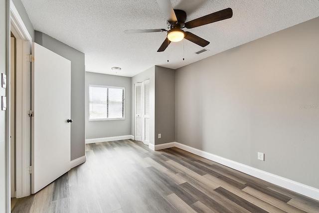 1508 Adams Cir E, Largo, FL 33771 - unfurnished bedroom with wood finished floors, a closet, a textured ceiling, and a ceiling fan