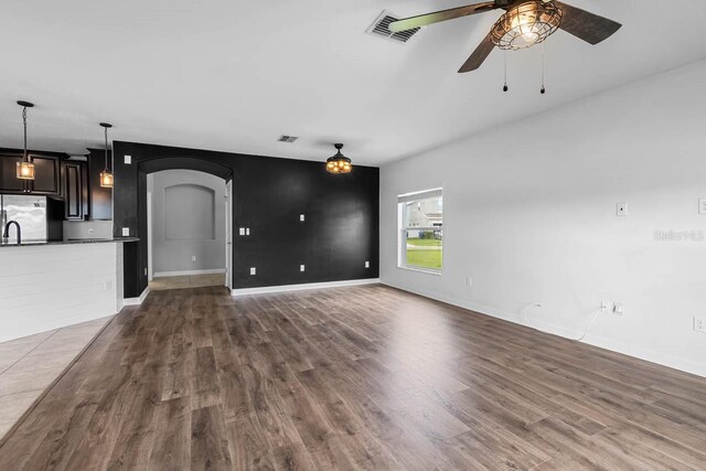 1821 Hawks View Dr, Ruskin, FL 33570 - unfurnished living room with arched walkways, ceiling fan, and dark wood-type flooring