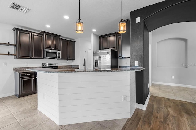 1821 Hawks View Dr, Ruskin, FL 33570 - kitchen with appliances with stainless steel finishes, dark stone countertops, arched walkways, pendant lighting, and a peninsula