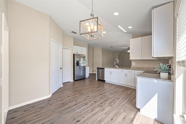 5131 Gato Del Sol Cir, Wesley Chapel, FL 33544 - kitchen with appliances with stainless steel finishes, a chandelier, light wood-type flooring, white cabinets, and recessed lighting