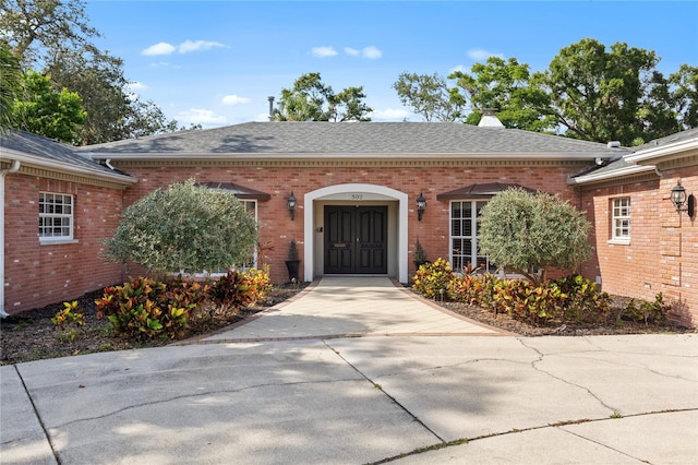 302 Eastleigh Dr, Belleair, FL 33756 - view of exterior entry featuring brick siding, a shingled roof, and a chimney