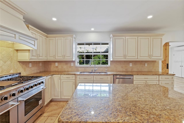 302 Eastleigh Dr, Belleair, FL 33756 - kitchen featuring appliances with stainless steel finishes, cream cabinetry, light stone countertops, custom exhaust hood, and arched walkways