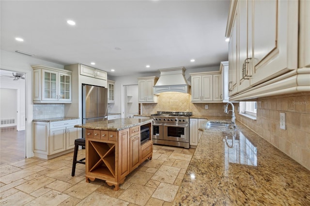 302 Eastleigh Dr, Belleair, FL 33756 - kitchen with premium range hood, stainless steel appliances, backsplash, light stone countertops, and recessed lighting