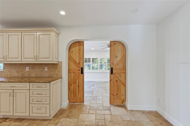 302 Eastleigh Dr, Belleair, FL 33756 - kitchen with cream cabinetry, arched walkways, stone tile floors, tasteful backsplash, and recessed lighting