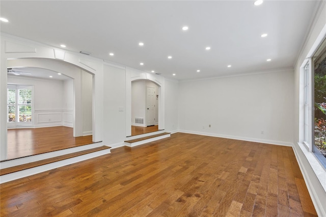 302 Eastleigh Dr, Belleair, FL 33756 - spare room with arched walkways, ornamental molding, wood finished floors, a ceiling fan, and a decorative wall