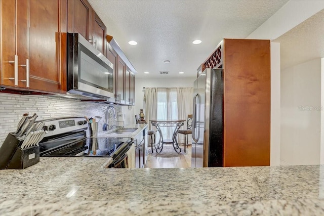 2078 Sunset Point Rd Unit 83, Clearwater, FL 33765 - kitchen with stainless steel appliances, decorative backsplash, recessed lighting, a textured ceiling, and light stone counters