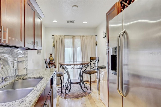 2078 Sunset Point Rd Unit 83, Clearwater, FL 33765 - kitchen featuring stainless steel refrigerator with ice dispenser, light wood-type flooring, tasteful backsplash, light stone countertops, and recessed lighting