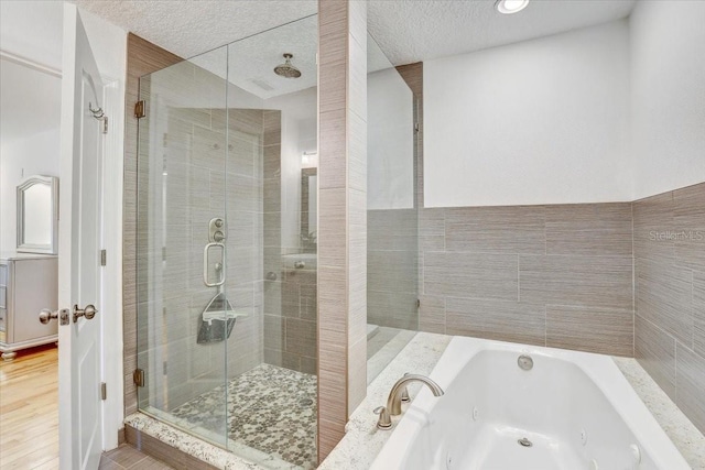 2078 Sunset Point Rd Unit 83, Clearwater, FL 33765 - bathroom featuring a shower stall, a tub with jets, a textured ceiling, and wood finished floors