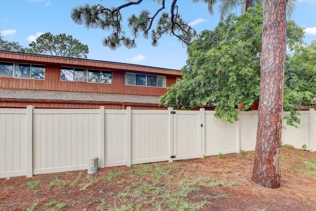 2078 Sunset Point Rd Unit 83, Clearwater, FL 33765 - view of property exterior with roof with shingles, a fenced backyard, and a gate