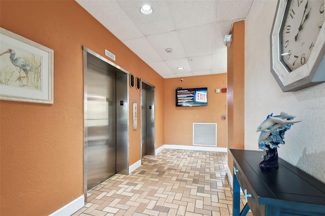 255 Dolphin Pt Unit 207, Clearwater Beach, FL 33767 - hallway featuring elevator, a paneled ceiling, recessed lighting, and brick patterned floors