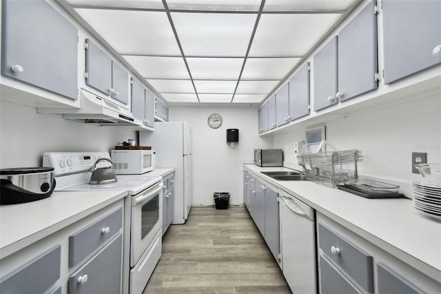 255 Dolphin Pt Unit 207, Clearwater Beach, FL 33767 - kitchen with white appliances, under cabinet range hood, gray cabinetry, light wood-style floors, and light countertops