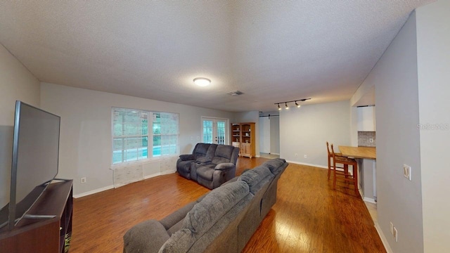 6605 Foxmoor Dr, Zephyrhills, FL 33542 - living room featuring wood finished floors, a textured ceiling, rail lighting, and french doors