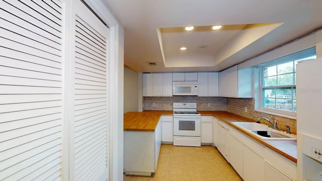 6605 Foxmoor Dr, Zephyrhills, FL 33542 - kitchen with white appliances, backsplash, light tile patterned floors, a raised ceiling, and recessed lighting