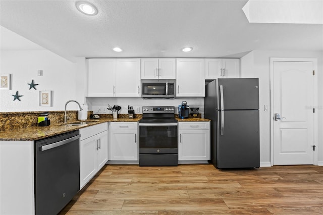 12000 Gulf Blvd Unit 506N, Treasure Island, FL 33706 - kitchen featuring stainless steel appliances, white cabinets, a peninsula, dark stone counters, and light wood-style floors
