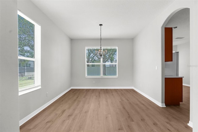 5015 58th Ter E, Bradenton, FL 34203 - unfurnished dining area featuring light wood-type flooring, arched walkways, and a chandelier